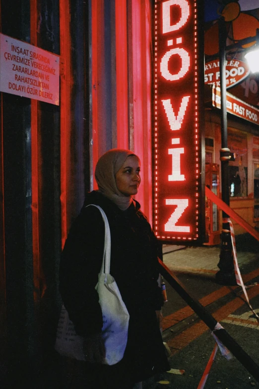 the woman is standing in front of the neon sign