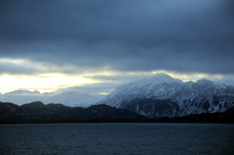 a large body of water sitting under a large snowy mountain