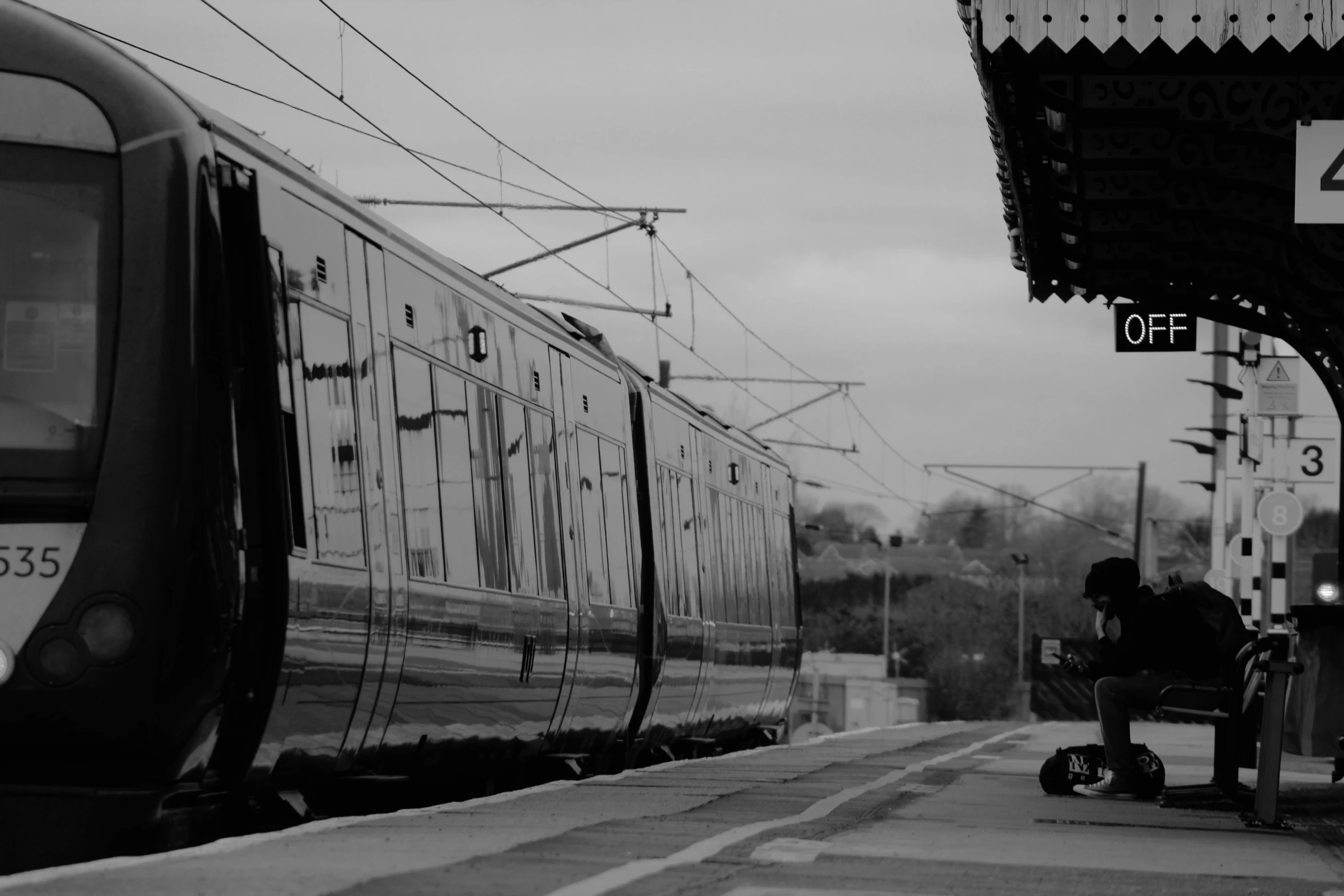 a man sits on a bench near a train