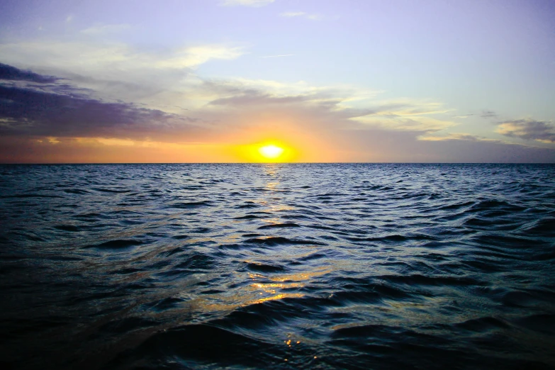 the sun rises over the horizon of a calm ocean