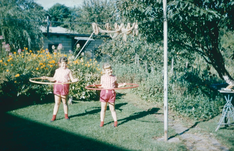 two children are hula hooping in the yard