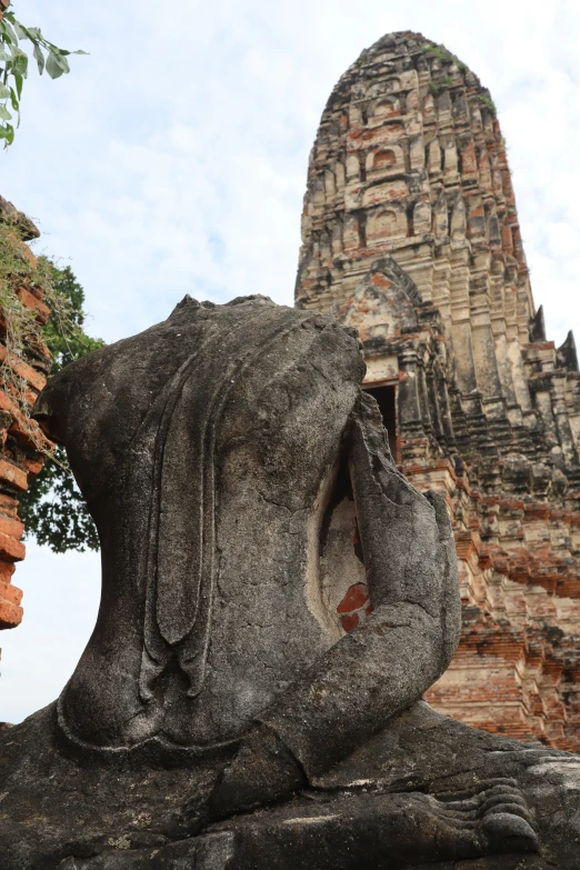 a stone statue is facing towards a brick structure