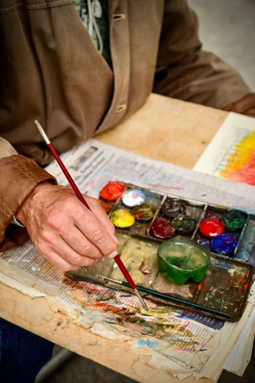 a man holding a painting brush near a palette