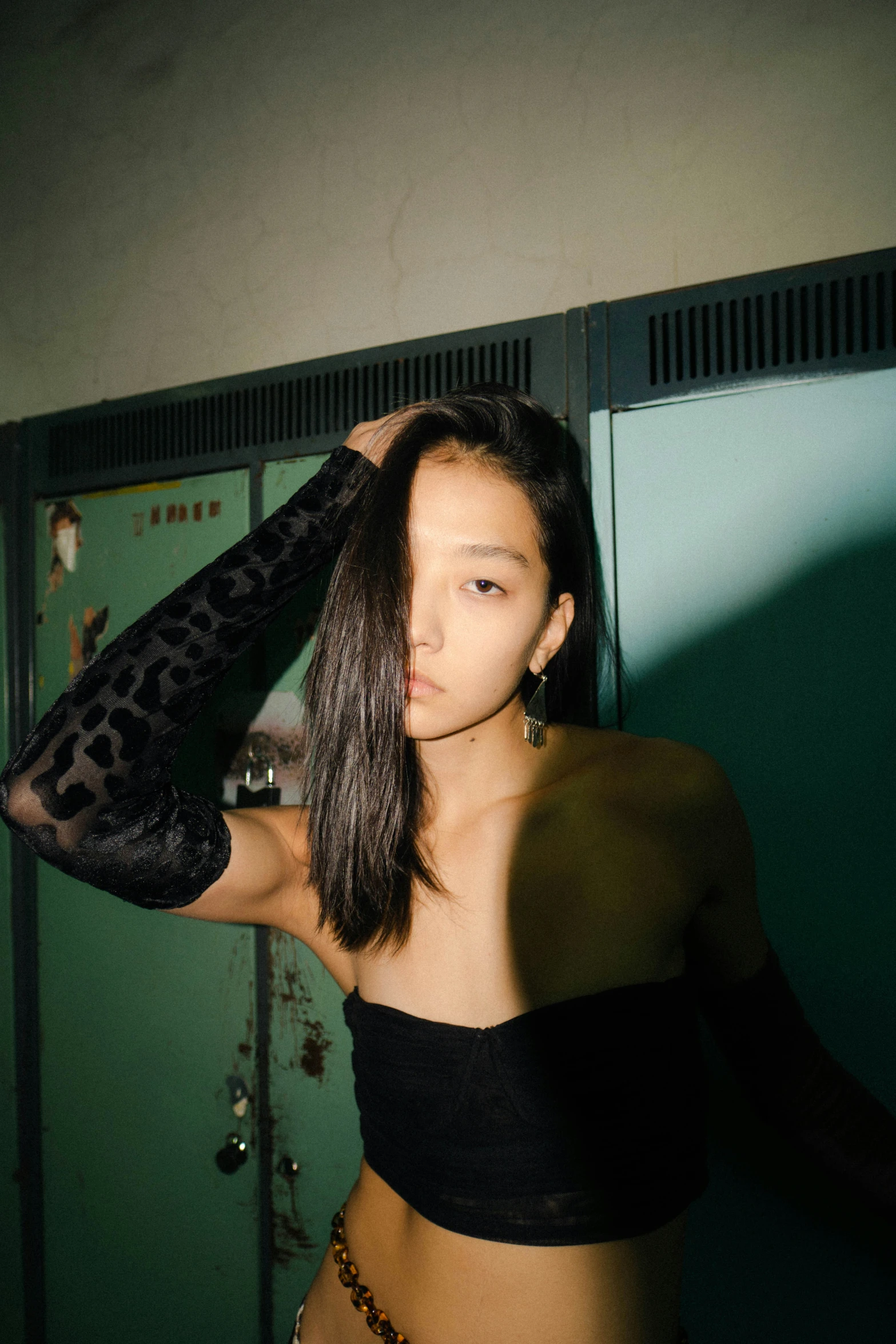 a woman in a black crop top is standing by a locker