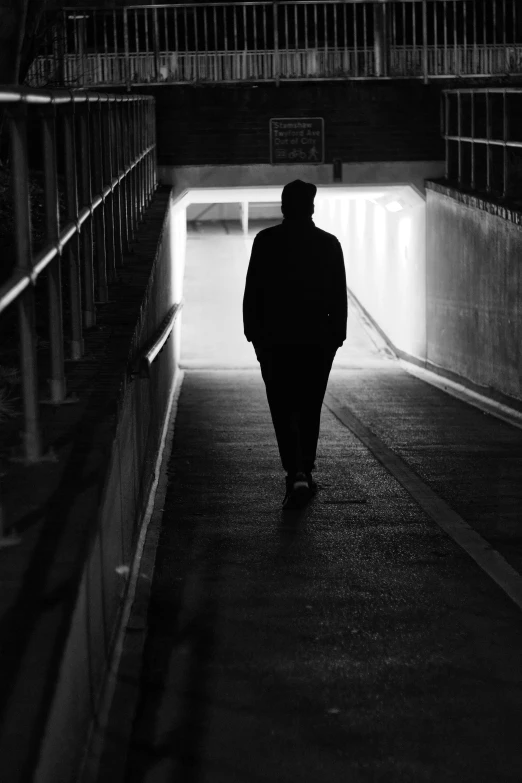 the man is walking down the walkway in the tunnel