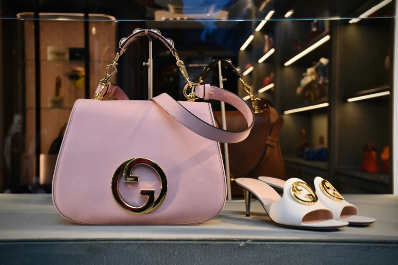 a pink purse with gold hardware on it and white shoes on display