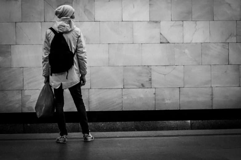 black and white pograph of a woman walking with bags on the sidewalk