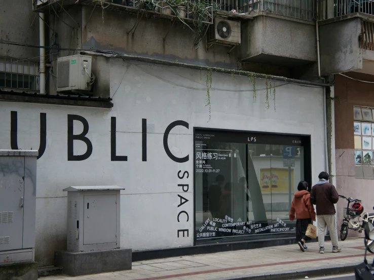 a pair of people walking past a large window display