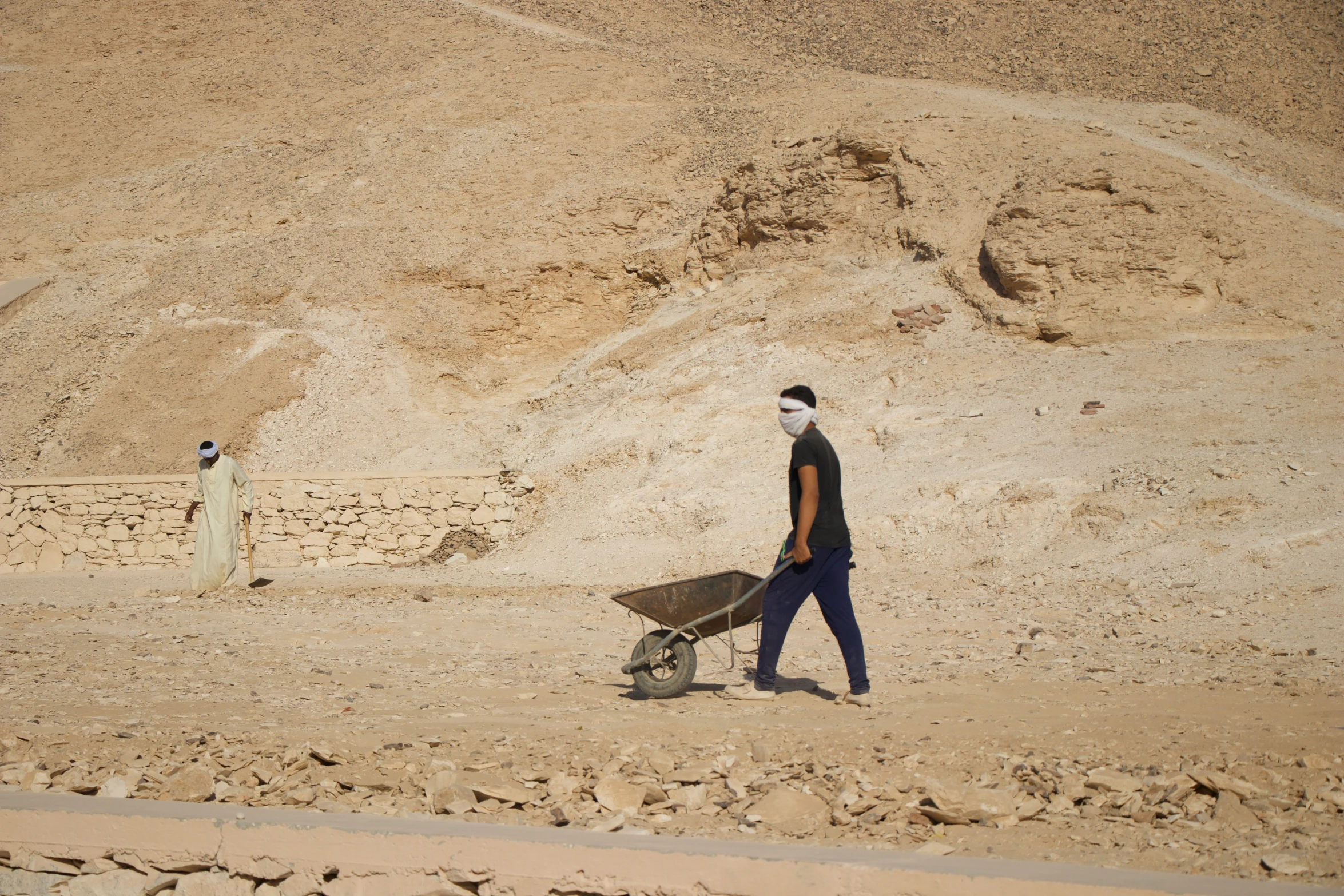 two men walking in the desert near some rocks