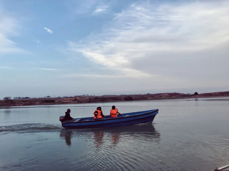 three people sitting in the bow of a boat with a blue ocean and mountains in the background