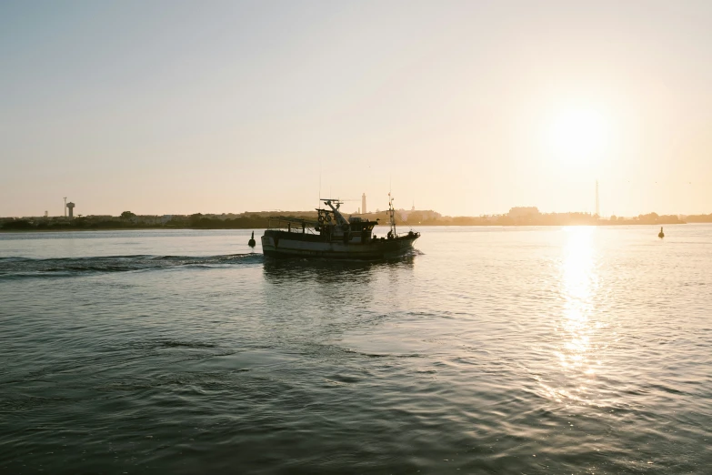 a boat sails on the ocean at sunset