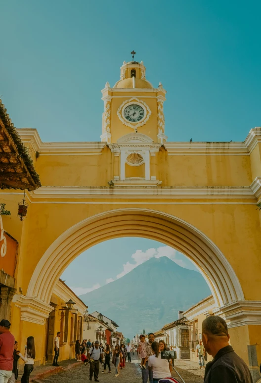 people are walking under a yellow and white archway