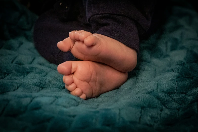 an infant's hands and toes laying on a blanket