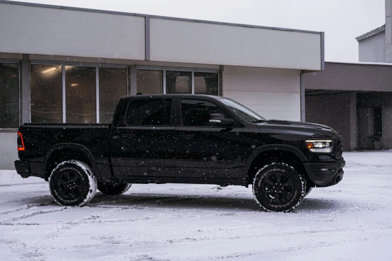 a black truck parked outside a store in the snow