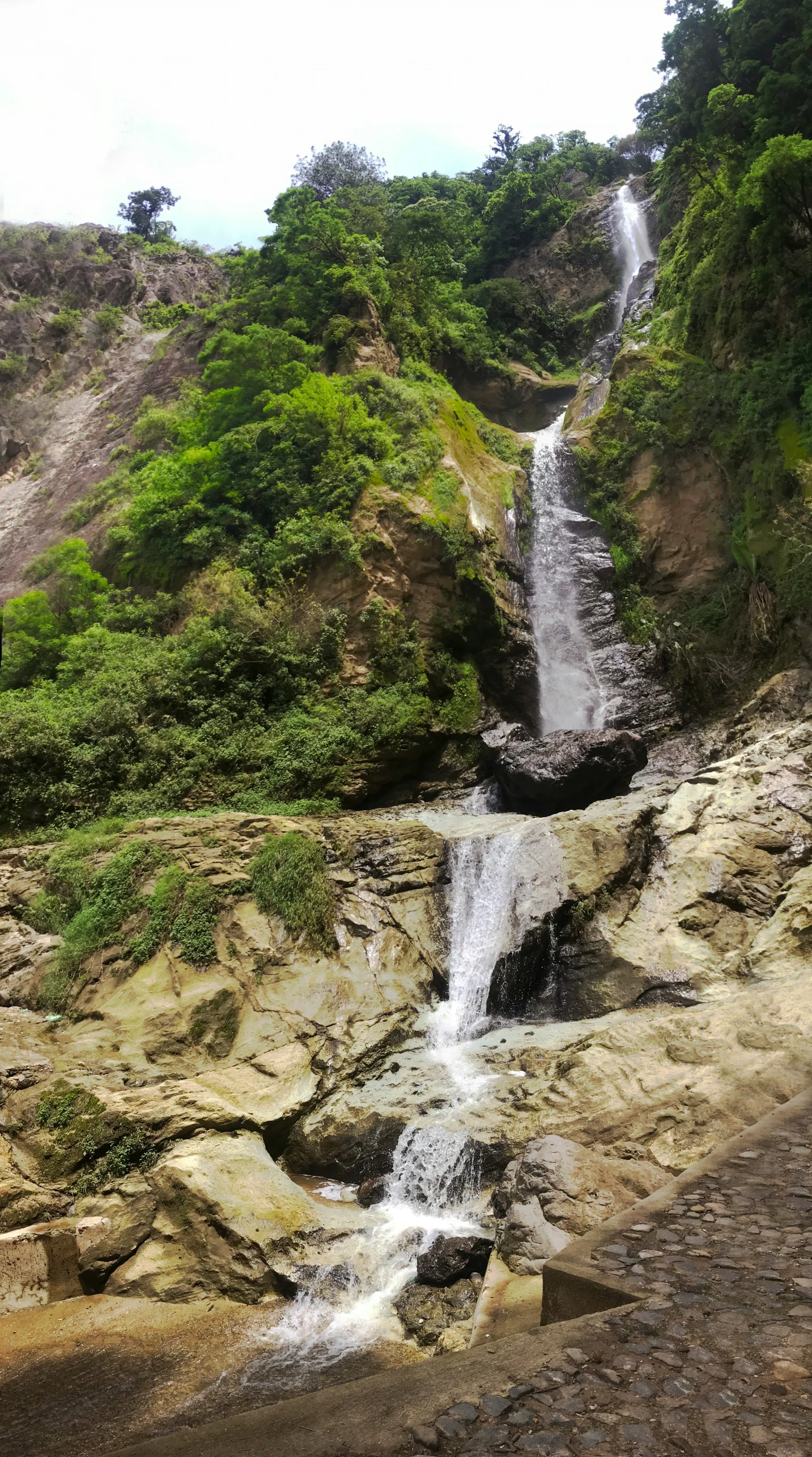 a small waterfall in the middle of a rocky forest