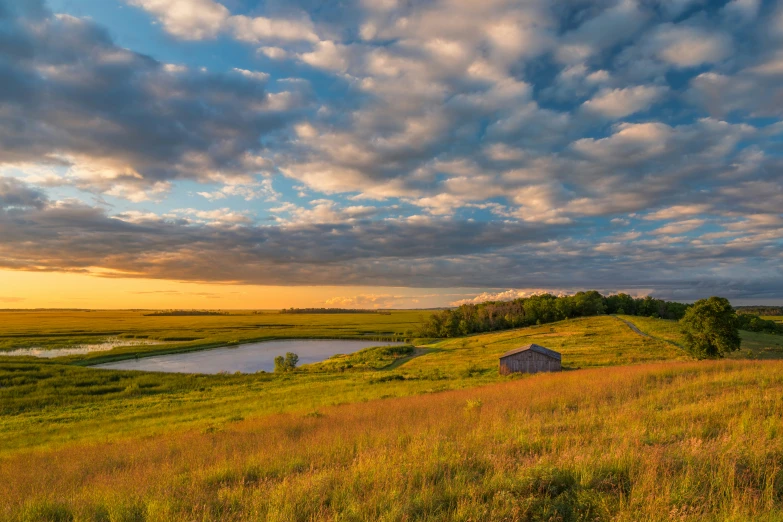 a grassy hill surrounded by water and clouds