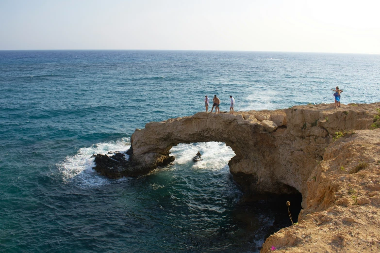 some people standing on a ledge in the water