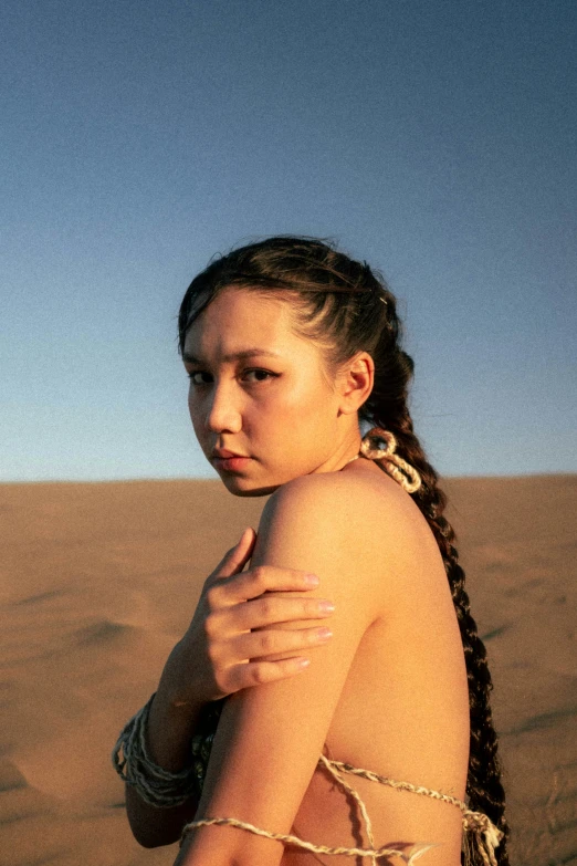 a girl standing in the desert with arms folded