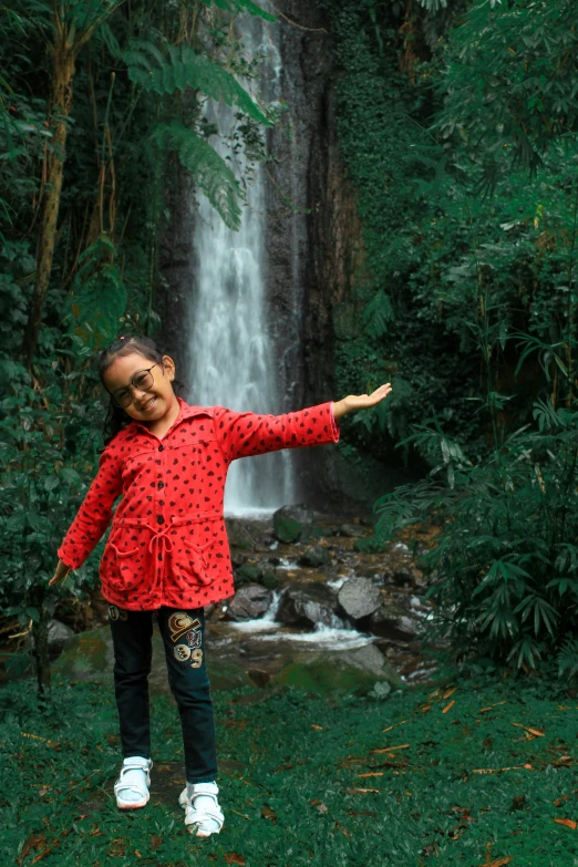 there is a girl that is playing near the waterfall