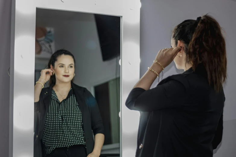 a woman standing in front of a mirror while putting on makeup