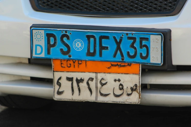 the back end of a white car with two license plates