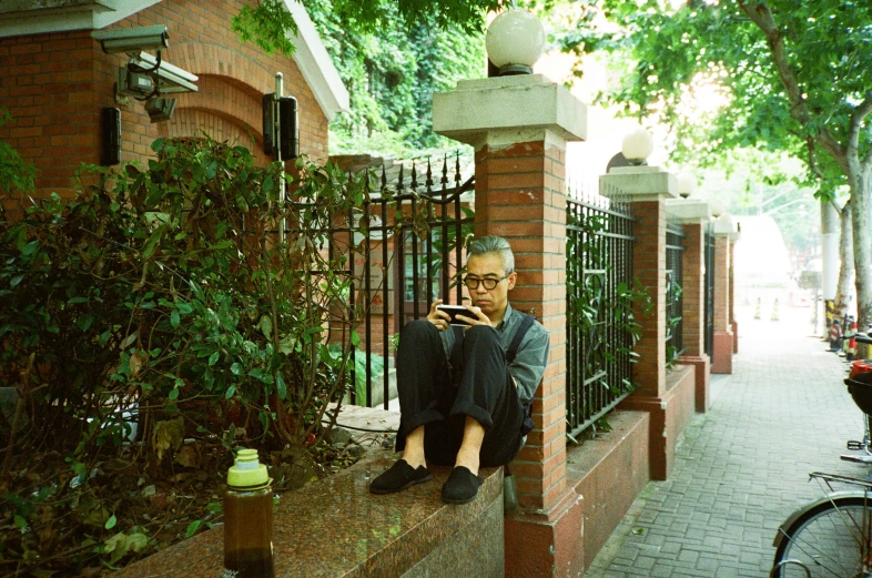 a man sitting on the side of a street with a cell phone