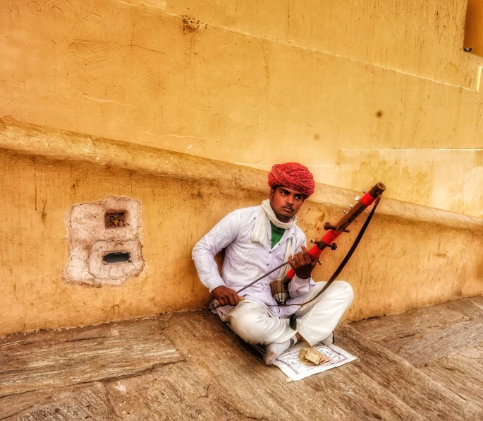 a man is sitting by the wall with a pipe