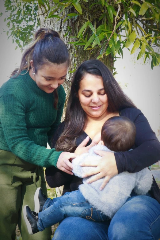 two women are sitting on a bench holding a baby