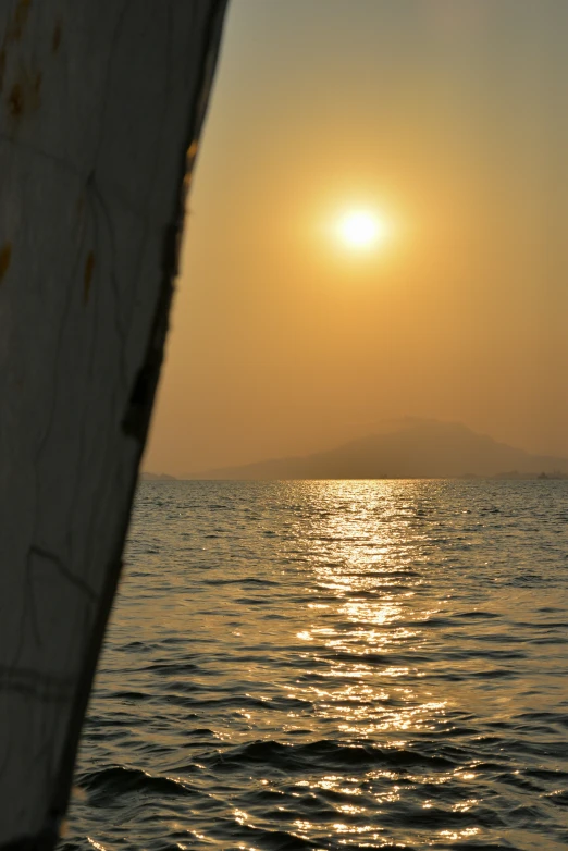 sunset over the ocean from a boat near an island