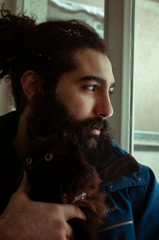 a man in jacket holding a cat while looking at it