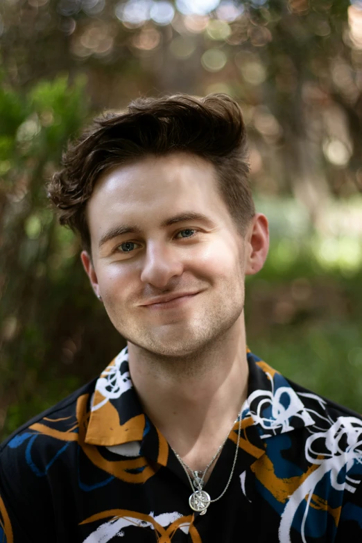 a young man with brown hair wearing a flowered shirt