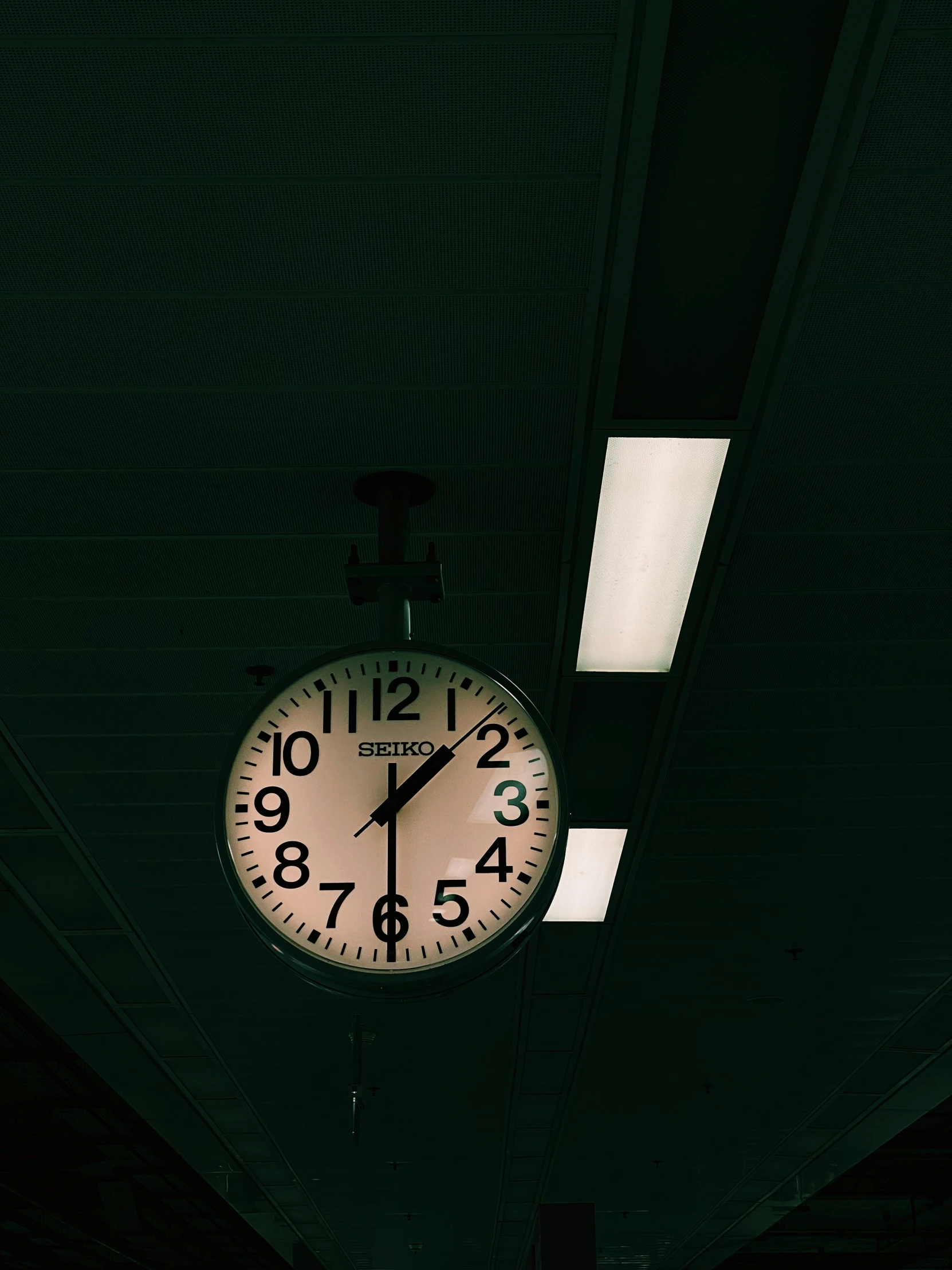 a large clock on the ceiling in the dark