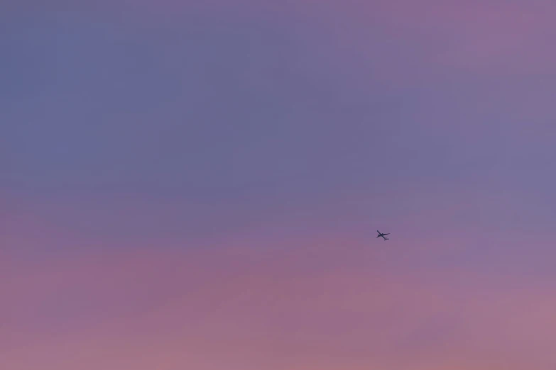 plane flying high above some pink clouds in the sky