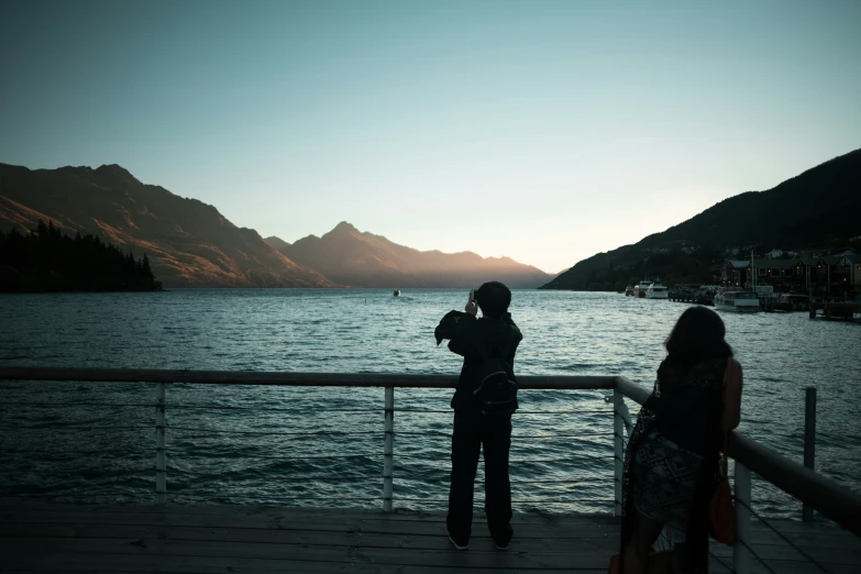 two people standing next to each other on a pier