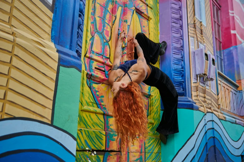 a woman with red hair and long legs climbing the side of a building