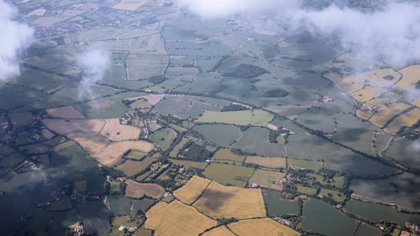an aerial view of farmland and clouds on a sunny day