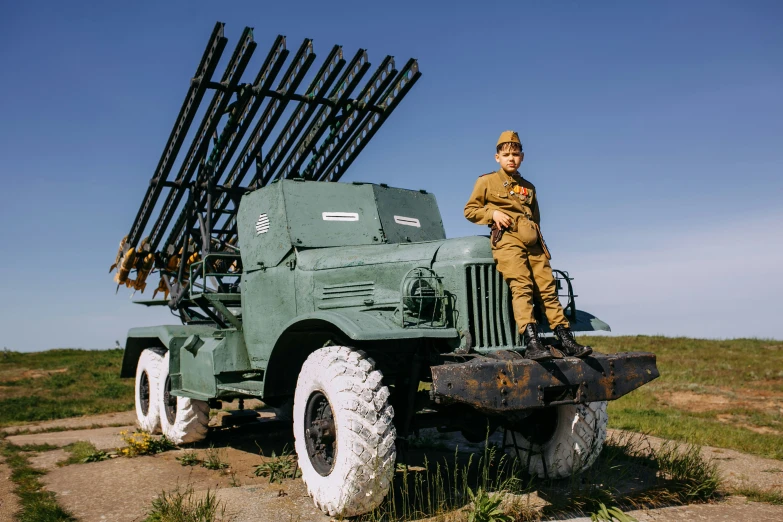 a man standing on a military truck near a fence