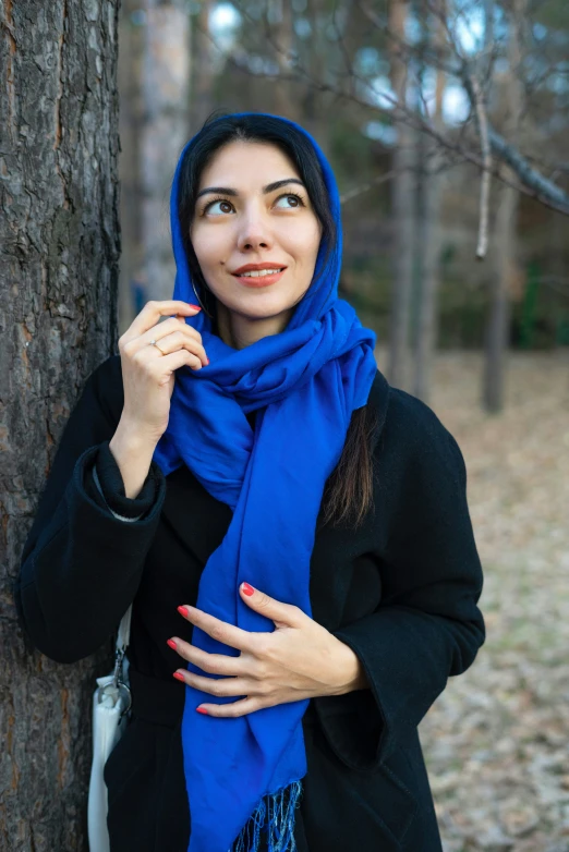 a young woman in the forest leaning on a tree