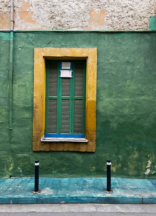 green wall with windows and yellow frame on street