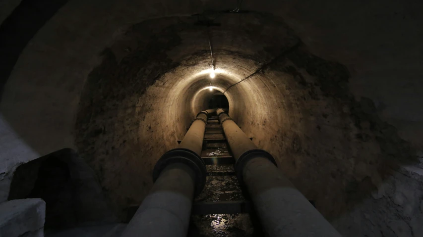 a person stands at the end of a long, dimly lit, tube walk