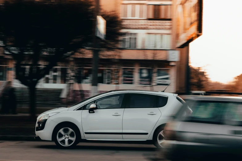 there is a small white car on the street next to a building