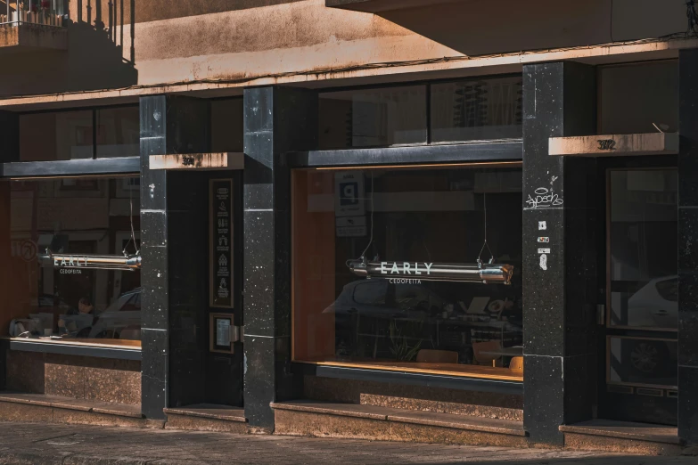 an outdoor storefront with black doors has a white clock