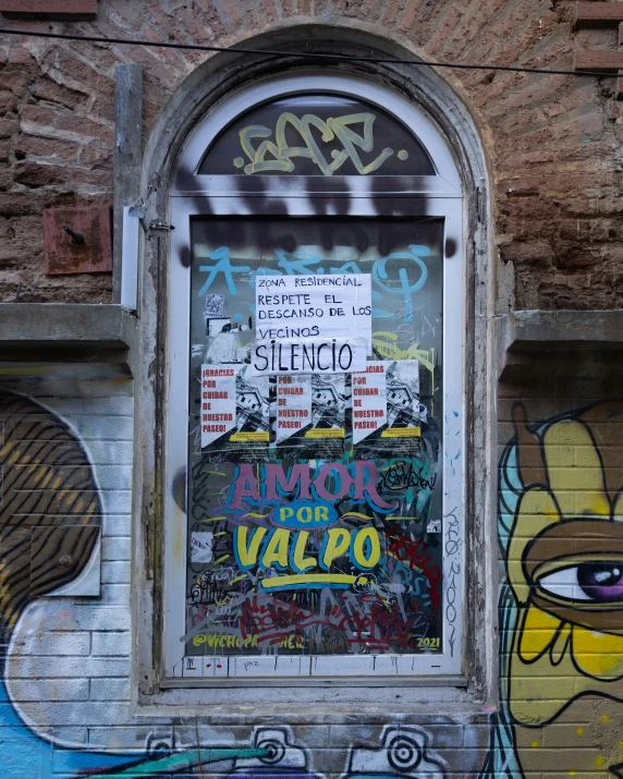 graffiti on a window and door next to a brick wall