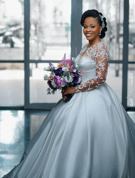 a bride wearing a long sleeved white wedding gown with sheer top