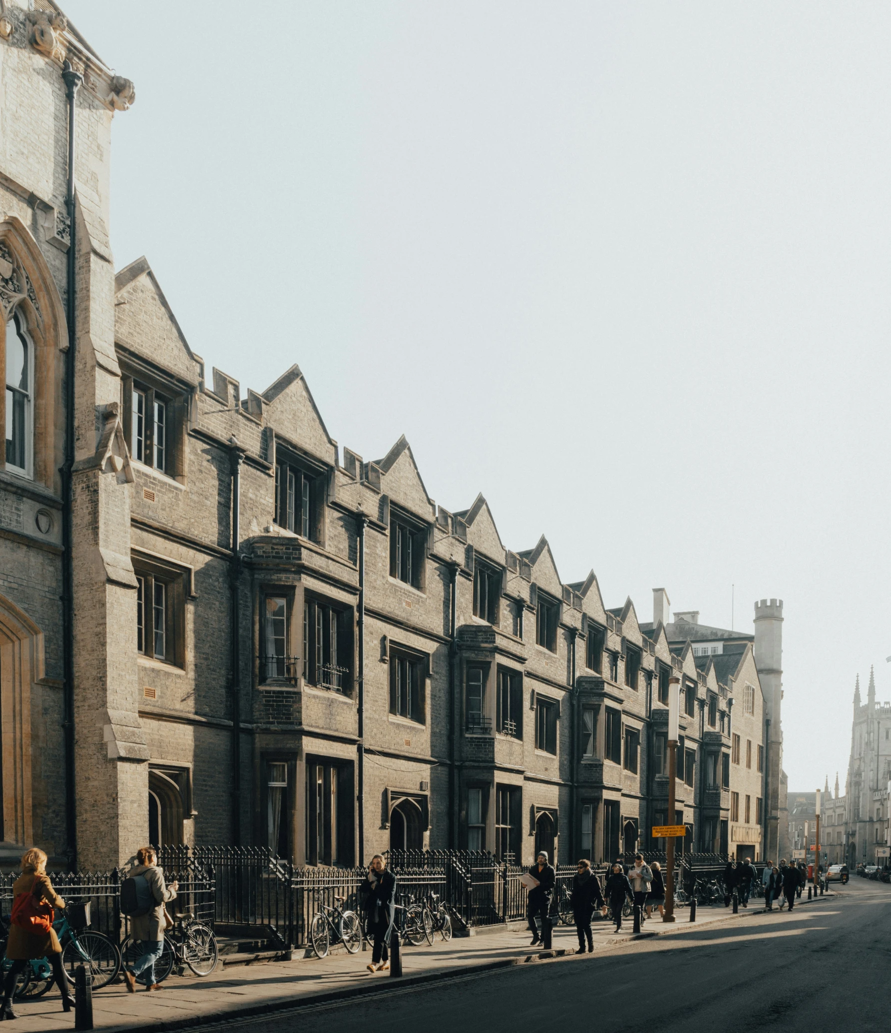 people riding bikes along a sidewalk in the middle of an old city