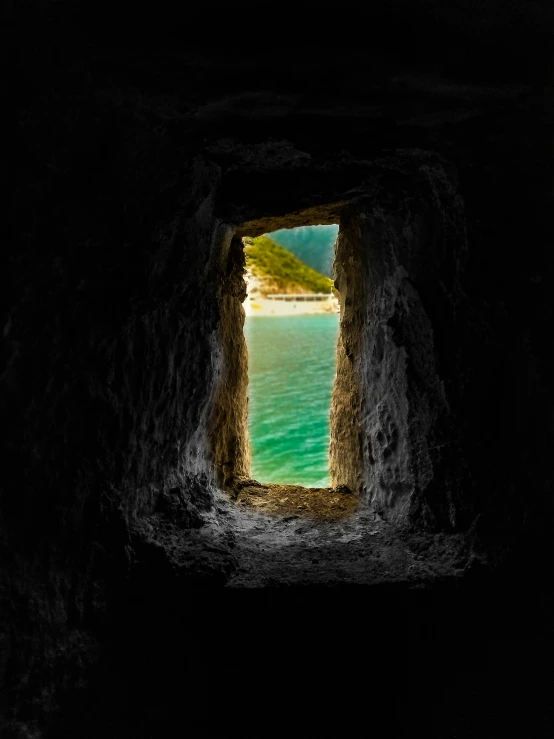 a view out the opening of a tunnel, with water in it