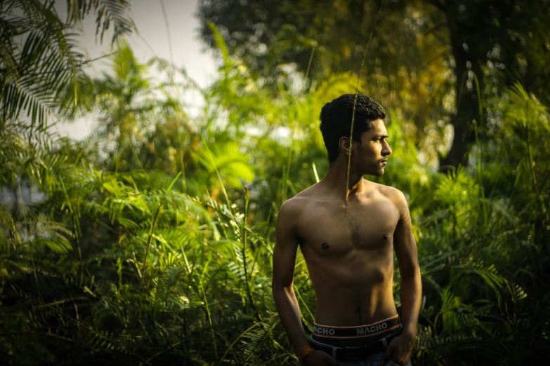 a man in the woods standing with his shirtless body showing