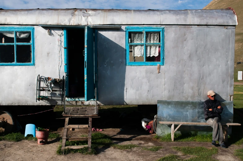 an old man stands by a trailer with its door open