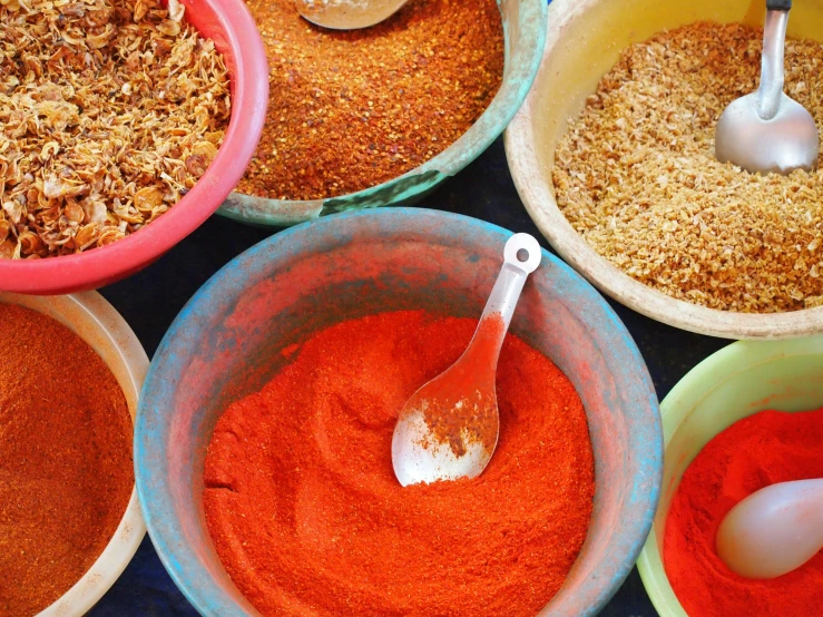 several bowls full of various spices on a table