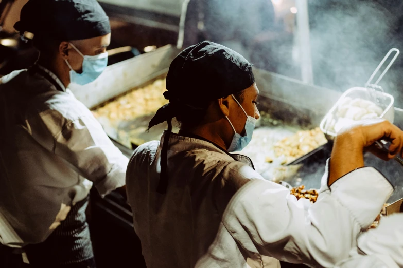 people in aprons frying some food in a pan